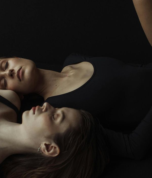Woman in a serene yoga pose against a dark, calm background.